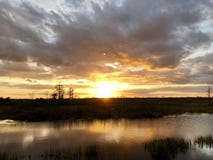 Sunset in the swamps. Giant orange sun sets behind the bayou of a cypress swamp and reflects in the river stock photo Sunset in the swamps. Giant orange sun sets behind the bayou of a cypress swamp and reflects in the river stock photo