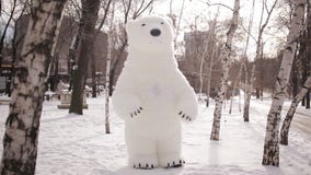 Giant puppets bear walks on a snow-covered birch forest