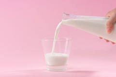 Gietende melk in glas op roze achtergrond Royalty-vrije Stock Foto's Gietende melk in glas op roze achtergrond Royalty-vrije Stock Foto's