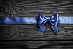 Gift blue bow and ribbon on a black wooden background stock photography Gift blue bow and ribbon on a black wooden background stock photography
