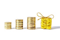 Gift box in gold packing bandaged with a bow next to coins column close-up isolated Stock Photos Gift box in gold packing bandaged with a bow next to coins column close-up isolated Stock Photos