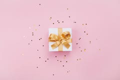 Gift or present box and stars confetti on pink pastel table top view. Flat lay composition for birthday, mother day or wedding.