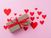 Giftvakje in het pakpapier van kraftpapier met een rood lint op een roze backgr Stock Afbeelding Giftvakje in het pakpapier van kraftpapier met een rood lint op een roze backgr Stock Afbeelding