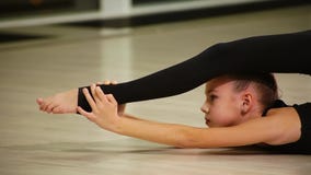 Gimnasta artístico lindo del niño femenino del primer en ropa de deportes negra hacer calentamiento en gimnasio y realizar el mús Gimnasta artístico lindo del niño femenino del primer en ropa de deportes negra hacer calentamiento en gimnasio y realizar el mús