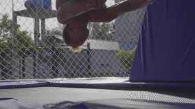 Ginnasta professionista che salta sul trampolino e che fa i trucchi al rallentatore stock footage Ginnasta professionista che salta sul trampolino e che fa i trucchi al rallentatore stock footage