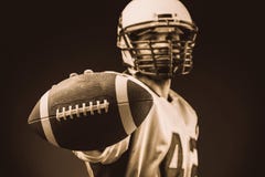 Giocatore di football americano che tiene la palla in sue mani davanti alla macchina fotografica Football americano di concetto, fotografia stock libera da diritti Giocatore di football americano che tiene la palla in sue mani davanti alla macchina fotografica Football americano di concetto, fotografia stock libera da diritti