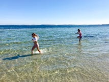 Gioco felice dei bambini allegro su una spiaggia in mare fotografia stock Gioco felice dei bambini allegro su una spiaggia in mare fotografia stock