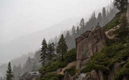 Giorno piovoso nelle montagne con la scogliera rocciosa e gli alberi silhoueted fotografie stock libere da diritti Giorno piovoso nelle montagne con la scogliera rocciosa e gli alberi silhoueted fotografie stock libere da diritti