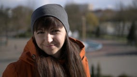 Giovane bella condizione castana sulla via, guardando alla macchina fotografica ed ai sorrisi Primo piano immagine stock libera da diritti Giovane bella condizione castana sulla via, guardando alla macchina fotografica ed ai sorrisi Primo piano immagine stock libera da diritti