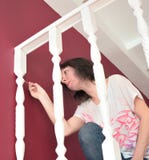 Giovane bella pittura della donna un ballustrade del bordo bianco con una spazzola fotografia stock libera da diritti Giovane bella pittura della donna un ballustrade del bordo bianco con una spazzola fotografia stock libera da diritti