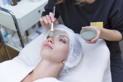 Giovane bella ragazza che riceve maschera facciale con la spazzola nel salone di bellezza della stazione termale - all'interno immagine stock Giovane bella ragazza che riceve maschera facciale con la spazzola nel salone di bellezza della stazione termale - all'interno immagine stock