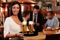 Giovane cameriera di bar felice con birra fotografie stock libere da diritti Giovane cameriera di bar felice con birra fotografie stock libere da diritti