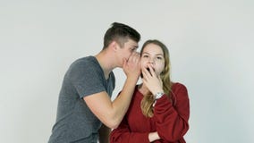 Giovane che bisbiglia un segreto ad una giovane donna sorpresa Il giovane dice un segreto alla ragazza fotografie stock Giovane che bisbiglia un segreto ad una giovane donna sorpresa Il giovane dice un segreto alla ragazza fotografie stock