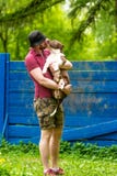 Giovane che gode di un giorno soleggiato nel parco con il suo cane Il proprietario dell'animale domestico che riceve un bacio lec fotografia stock Giovane che gode di un giorno soleggiato nel parco con il suo cane Il proprietario dell'animale domestico che riceve un bacio lec fotografia stock