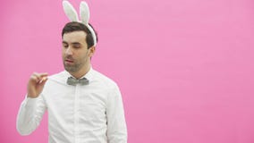 Giovane condizione bella del ragazzo su un fondo rosa Un uomo con le orecchie della ressa sulla sua testa Un uomo che tiene una c stock footage Giovane condizione bella del ragazzo su un fondo rosa Un uomo con le orecchie della ressa sulla sua testa Un uomo che tiene una c stock footage