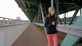 Giovane corridore femminile che pareggia sopra il ponte industriale Donna che fa gli sport in città video d archivio Giovane corridore femminile che pareggia sopra il ponte industriale Donna che fa gli sport in città video d archivio