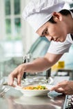 Giovane cuoco unico asiatico bello che placca sull'alimento immagine stock libera da diritti Giovane cuoco unico asiatico bello che placca sull'alimento immagine stock libera da diritti