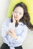 Giovane donna asiatica che parla sul telefono mentre mettendo sul letto Il punto di vista superiore della donna asiatica prende u fotografia stock Giovane donna asiatica che parla sul telefono mentre mettendo sul letto Il punto di vista superiore della donna asiatica prende u fotografia stock
