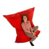 Giovane donna attraente che si siede sulla sedia rossa del sofà del beanbag per liv immagini stock Giovane donna attraente che si siede sulla sedia rossa del sofà del beanbag per liv immagini stock