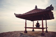 Giovane donna che fa pratica di yoga nel riparo del sole vicino all'oceano immagini stock libere da diritti Giovane donna che fa pratica di yoga nel riparo del sole vicino all'oceano immagini stock libere da diritti