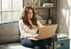 Giovane donna che lavora al computer portatile in appartamento del sottotetto Giovane donna che lavora al computer portatile in appartamento del sottotetto