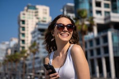 Giovane donna che per mezzo del telefono con la cuffia avricolare Orizzonte della citt? nel fondo fotografia stock libera da diritti Giovane donna che per mezzo del telefono con la cuffia avricolare Orizzonte della citt? nel fondo fotografia stock libera da diritti