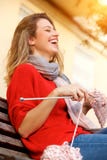 Giovane donna che ride e che tricotta maglione immagine stock libera da diritti Giovane donna che ride e che tricotta maglione immagine stock libera da diritti