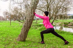 Giovane donna che si scalda e che allunga le gambe prima dell'correre su un inverno freddo, autunno del giorno dell'autunno in un fotografia stock libera da diritti Giovane donna che si scalda e che allunga le gambe prima dell'correre su un inverno freddo, autunno del giorno dell'autunno in un fotografia stock libera da diritti