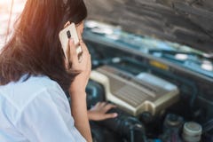 Giovane donna che si siede davanti alla sua automobile, prova dell'Asia a richiedere l'assistenza con la sua automobile ripartito immagini stock libere da diritti Giovane donna che si siede davanti alla sua automobile, prova dell'Asia a richiedere l'assistenza con la sua automobile ripartito immagini stock libere da diritti