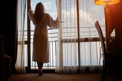 Giovane donna che sta sul balcone nella mattina fotografia stock Giovane donna che sta sul balcone nella mattina fotografia stock