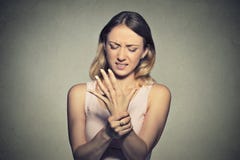 Giovane donna che tiene il suo dolore doloroso di distorsione del polso immagine stock libera da diritti Giovane donna che tiene il suo dolore doloroso di distorsione del polso immagine stock libera da diritti