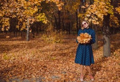 Giovane donna con capelli biondi che portano vestito blu che cammina nel parco di autunno fotografie stock libere da diritti Giovane donna con capelli biondi che portano vestito blu che cammina nel parco di autunno fotografie stock libere da diritti