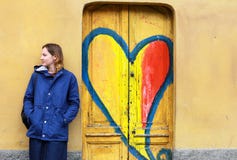Giovane donna contro la parete gialla e porte di legno con i graffiti fotografia stock libera da diritti Giovane donna contro la parete gialla e porte di legno con i graffiti fotografia stock libera da diritti