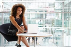 Giovane donna di affari che utilizza computer portatile nell'interno moderno immagine stock libera da diritti Giovane donna di affari che utilizza computer portatile nell'interno moderno immagine stock libera da diritti