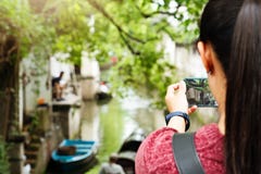 Giovane donna divertendosi nella città locale del canale in Cina con la macchina fotografica sullo smartphone che fa le immagini immagine stock libera da diritti Giovane donna divertendosi nella città locale del canale in Cina con la macchina fotografica sullo smartphone che fa le immagini immagine stock libera da diritti