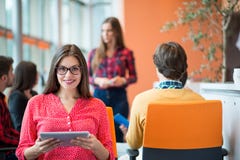 Giovane donna felice con il suo personale, gruppo di affari della gente nel fondo all'ufficio luminoso moderno all'interno immagini stock libere da diritti Giovane donna felice con il suo personale, gruppo di affari della gente nel fondo all'ufficio luminoso moderno all'interno immagini stock libere da diritti