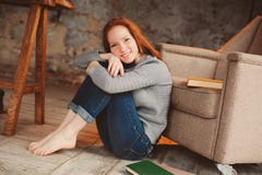 Giovane donna felice della testarossa che si rilassano a casa e libri di lettura fotografia stock Giovane donna felice della testarossa che si rilassano a casa e libri di lettura fotografia stock