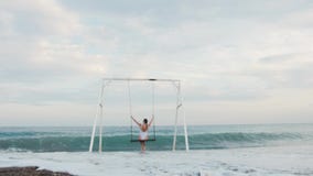 Giovane donna felice nella guida bianca del costume da bagno sull'oscillazione che gode della vista del mare Concetto di vacanza stock footage Giovane donna felice nella guida bianca del costume da bagno sull'oscillazione che gode della vista del mare Concetto di vacanza stock footage
