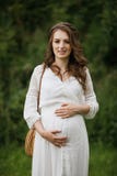 Giovane donna incinta che si rilassa nel parco all'aperto, pregnanc sano immagine stock libera da diritti Giovane donna incinta che si rilassa nel parco all'aperto, pregnanc sano immagine stock libera da diritti