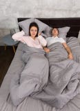Giovane donna infastidita che blocca le sue orecchie da un cuscino da rumore di immagine stock libera da diritti Giovane donna infastidita che blocca le sue orecchie da un cuscino da rumore di immagine stock libera da diritti