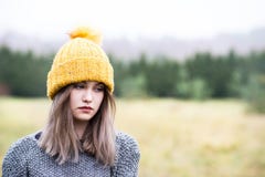 Giovane donna premurosa in cappuccio giallo di lana fotografia stock libera da diritti Giovane donna premurosa in cappuccio giallo di lana fotografia stock libera da diritti