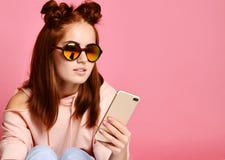 Giovane donna seria in occhiali d'avanguardia concentrati su informazioni che esaminano telefono immagine stock Giovane donna seria in occhiali d'avanguardia concentrati su informazioni che esaminano telefono immagine stock