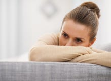 Giovane donna sollecitata che si siede sul sofà fotografia stock Giovane donna sollecitata che si siede sul sofà fotografia stock