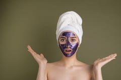 Giovane donna sorpresa attraente con la maschera di protezione porpora ed asciugamano della doccia sulla sua testa fotografie stock Giovane donna sorpresa attraente con la maschera di protezione porpora ed asciugamano della doccia sulla sua testa fotografie stock