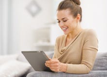 Giovane donna sorridente che si siede sullo strato e che lavora al pc della compressa fotografie stock libere da diritti Giovane donna sorridente che si siede sullo strato e che lavora al pc della compressa fotografie stock libere da diritti