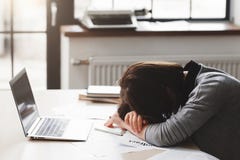 Giovane donna stanca che dorme alla scrivania fotografia stock Giovane donna stanca che dorme alla scrivania fotografia stock
