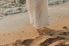 Giovane donna in vestito bianco che cammina sulla spiaggia immagine stock Giovane donna in vestito bianco che cammina sulla spiaggia immagine stock