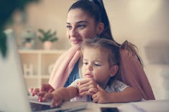 Giovane madre e figlia a casa che scrivono sul computer portatile immagine stock Giovane madre e figlia a casa che scrivono sul computer portatile immagine stock