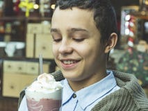 Giovane ragazzo felice sorridente adolescente castana, tenute in mani e bevande un frappé fotografie stock Giovane ragazzo felice sorridente adolescente castana, tenute in mani e bevande un frappé fotografie stock