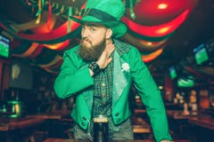 Giovane serio e pazzo nel supporto del vestito di St Patrick in pub e considerare macchina fotografica Tiene la mano vicino al co fotografie stock Giovane serio e pazzo nel supporto del vestito di St Patrick in pub e considerare macchina fotografica Tiene la mano vicino al co fotografie stock